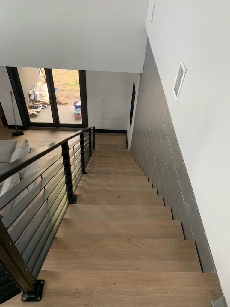 A wooden staircase with a metal railing leading up to the second floor of a house.