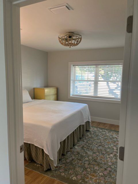 Bedroom with a bed, chest of drawers, rug, and a window with blinds.