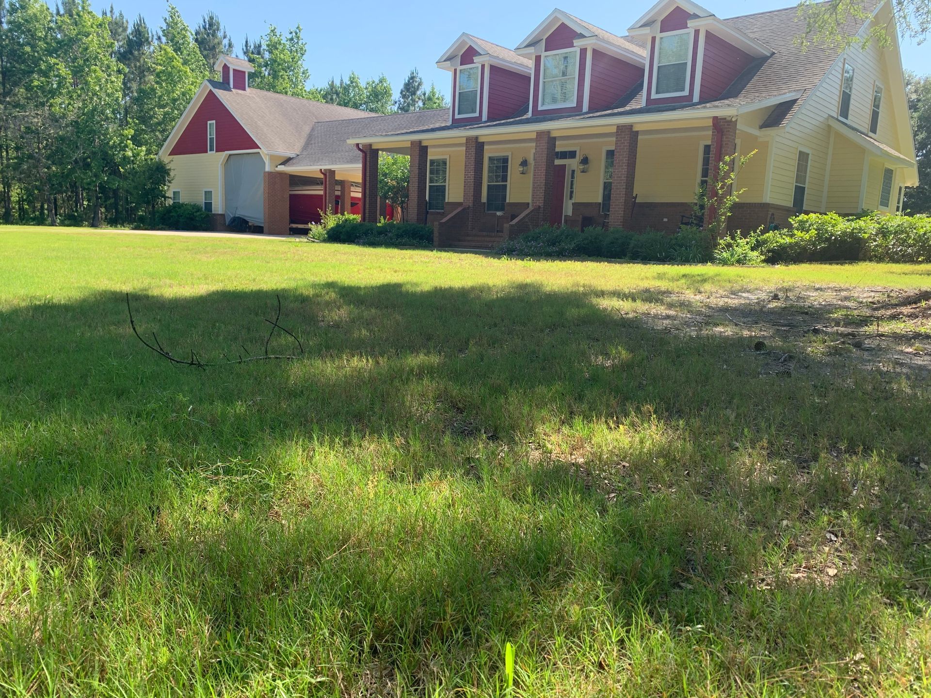 A large house with a red roof is sitting in the middle of a lush green field.