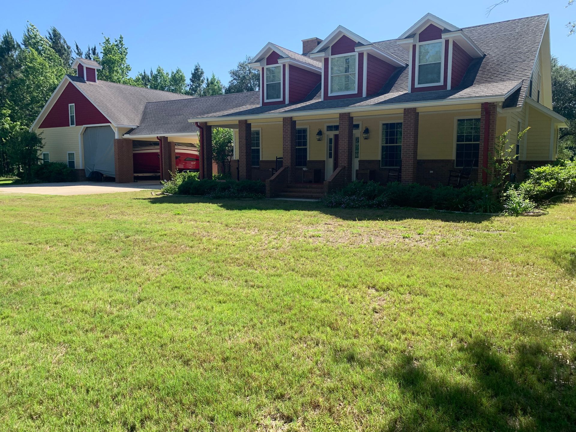 A large house with a red roof is sitting in the middle of a lush green field.