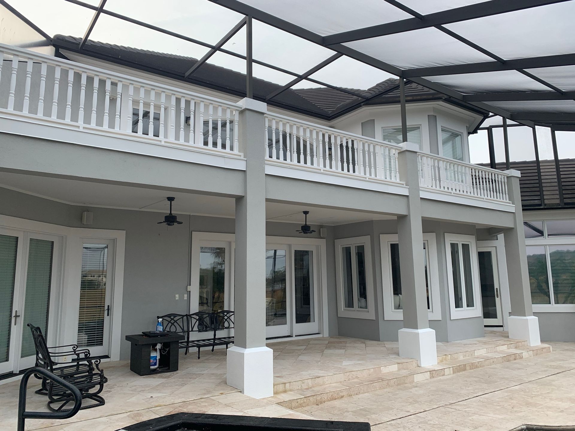 Modern white two-story patio with columns, balcony railing, and a covered roof structure