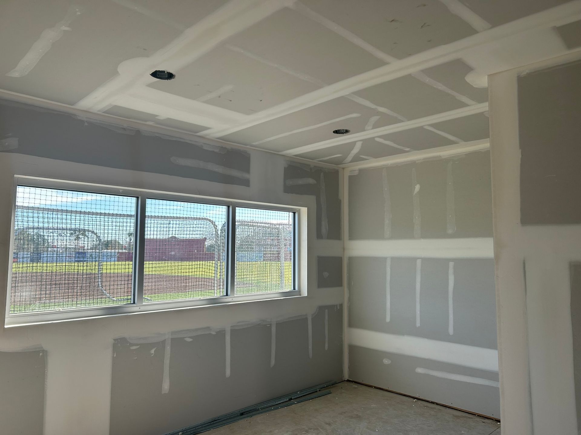 Unfinished room with drywall, taped seams, a large window, and a bare ceiling under construction