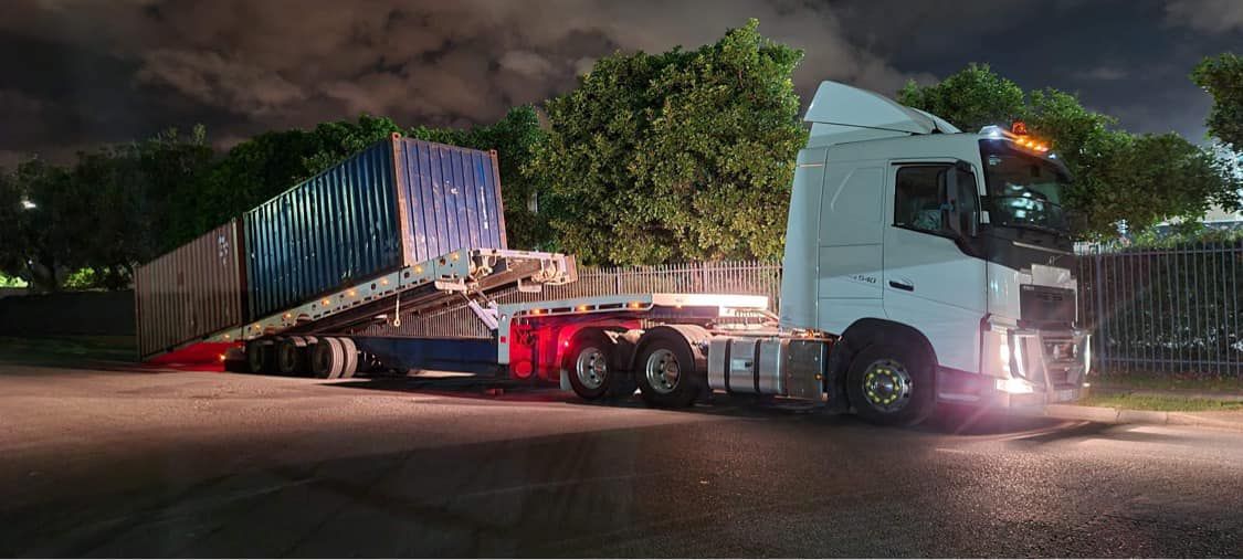 A Semi-truck With a Container Tilted at an Angle on a Road at Night — Fitzroy Towing & Transport in Emerald, QLD