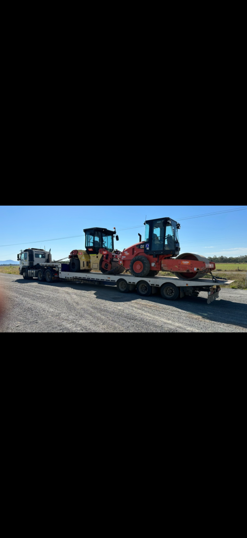 Two road rollers on a flatbed trailer, set against a blue sky, outside.— Fitzroy Towing & Transport in Parkhurst, QLD