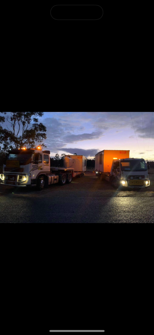 Two trucks parked with cargo at dusk.— Fitzroy Towing & Transport in Parkhurst, QLD