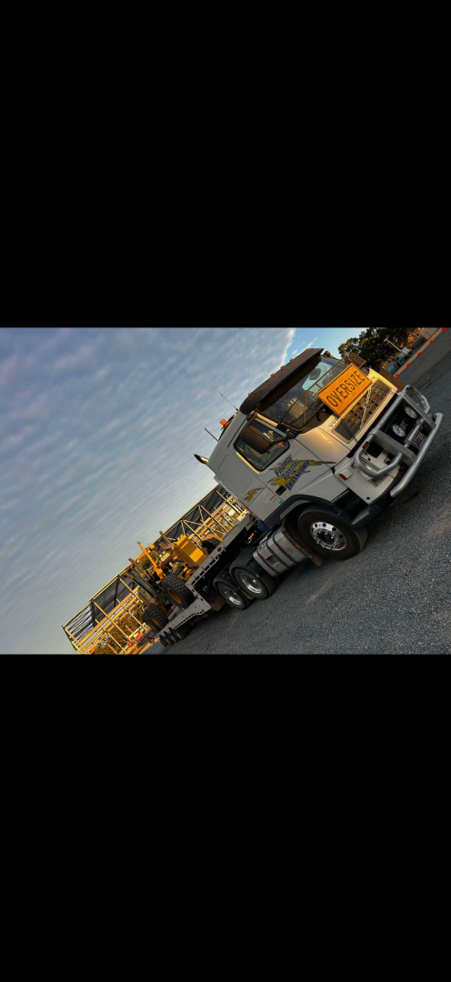 White Volvo truck with a trailer, at night. Trailer has graphics. Street scene.— Fitzroy Towing & Transport in Parkhurst, QLD
