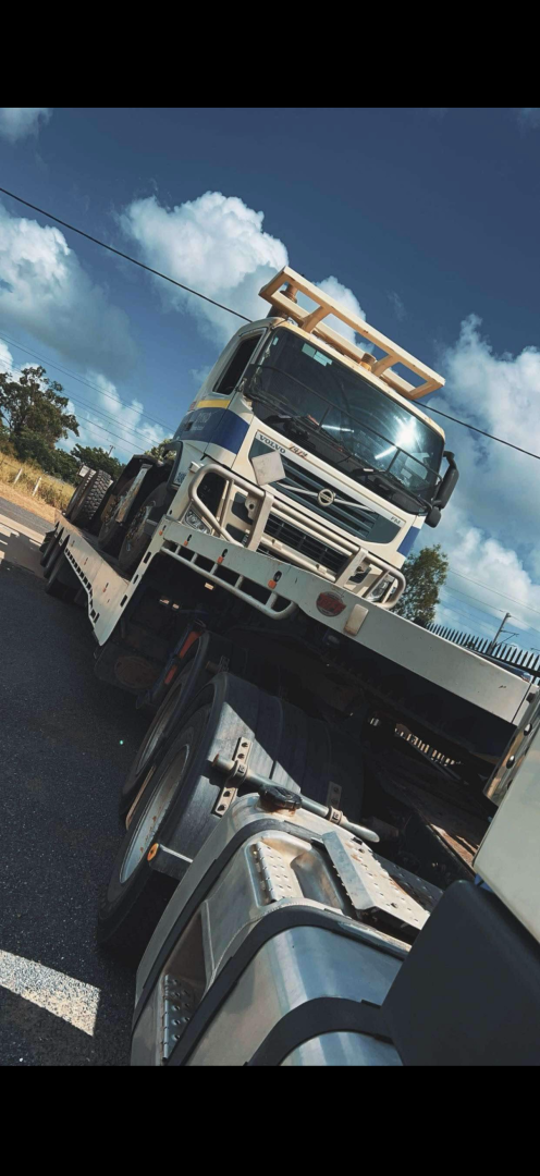 White truck on a trailer, angled towards the viewer on a sunny day.