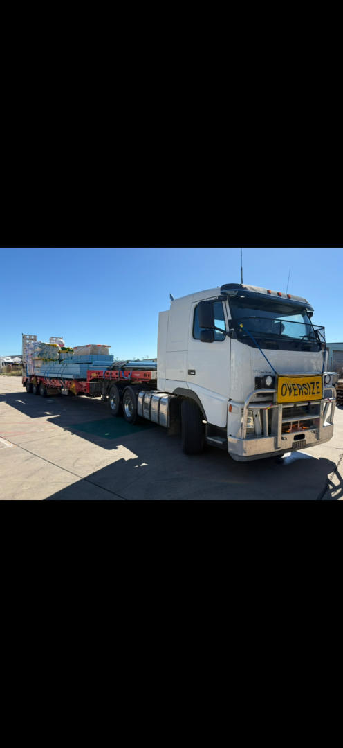 White semi-truck hauling oversized load on a clear day.