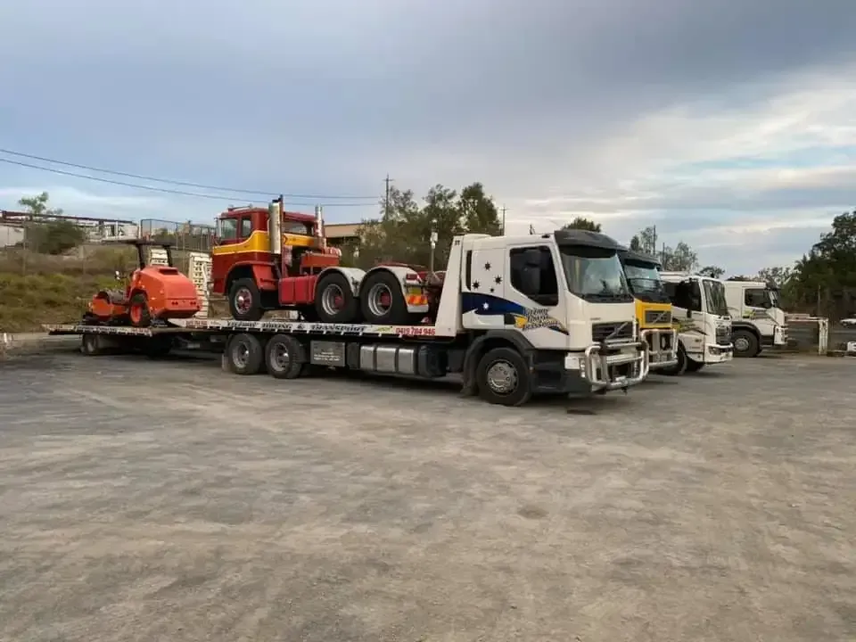 A Flatbed Truck Carrying a Vintage Red Truck — Fitzroy Towing & Transport in Parkhurst, QLD