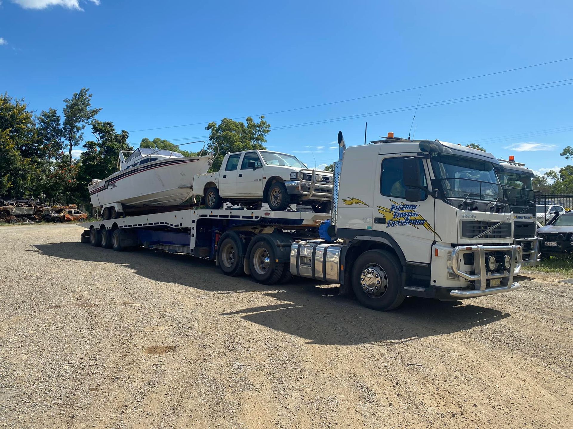A White Semi-truck Transports a Boat and a White Pickup Truck — Fitzroy Towing & Transport in Emerald, QLD