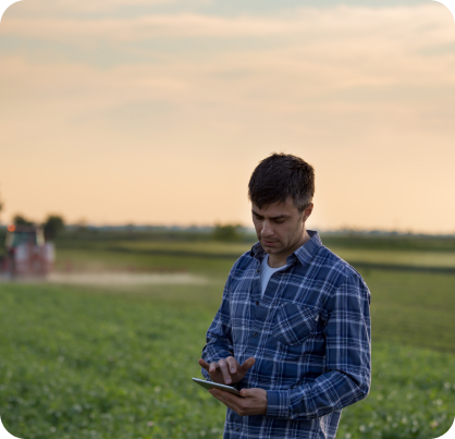 Um homem de camisa xadrez está falando ao celular em um campo