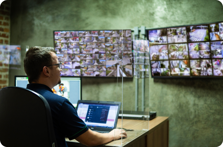 Um homem está sentado em uma mesa em frente a um monitor de computador.