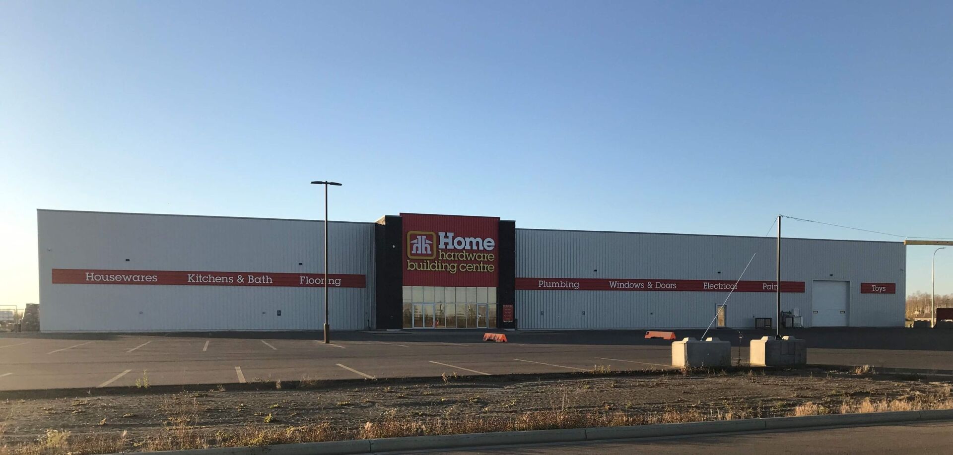 A large store with a lot of windows and a parking lot in front of it.