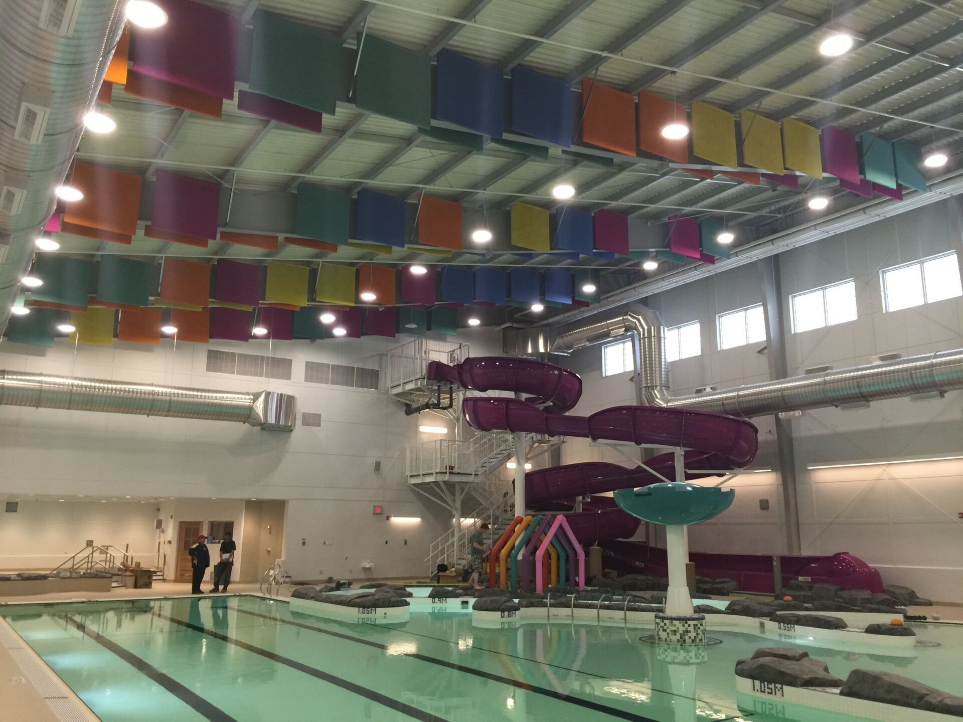 A large indoor swimming pool with a purple water slide.