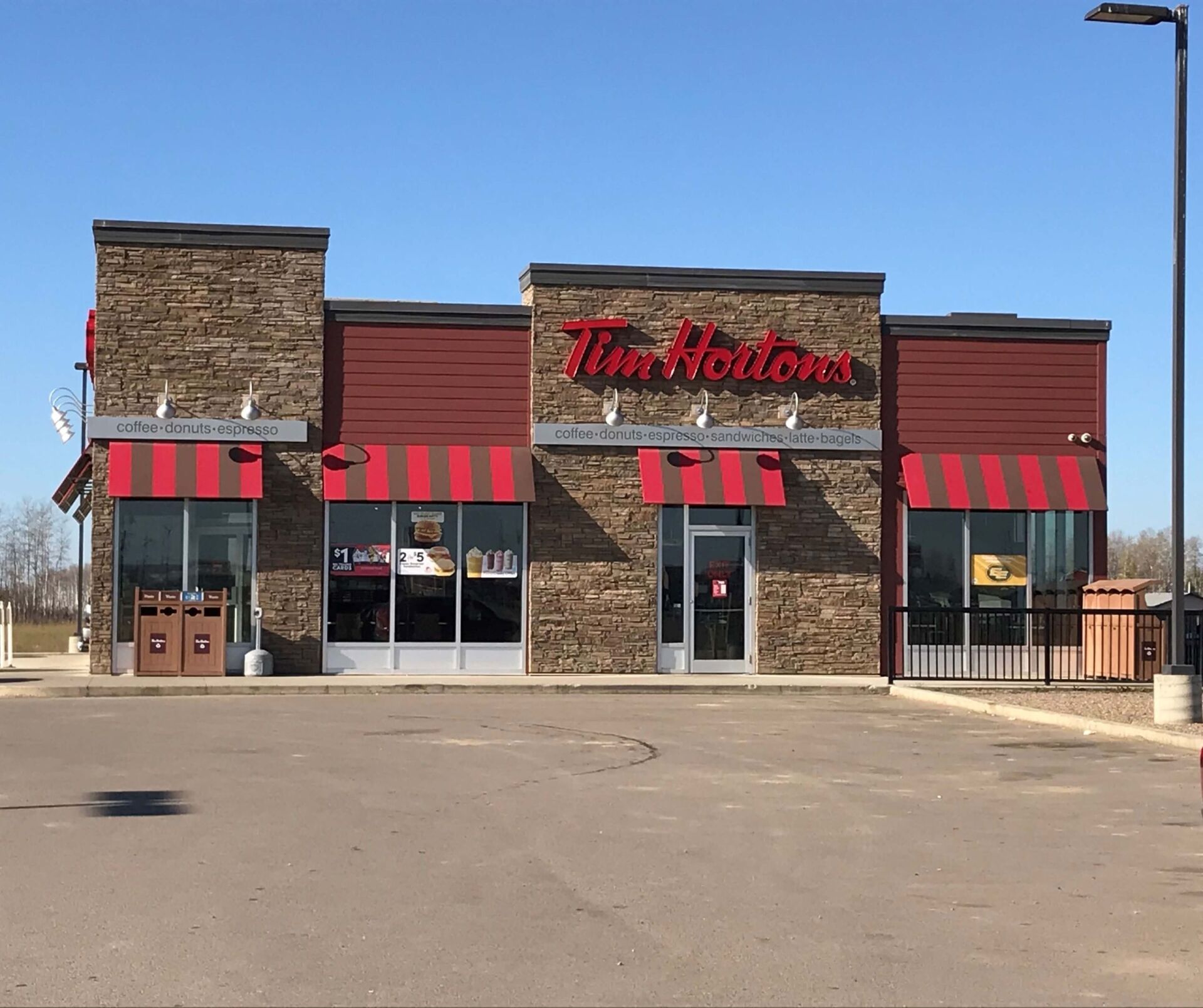 The outside of a tim hortons restaurant with red awnings