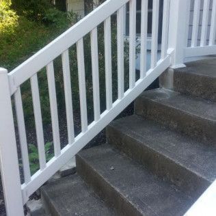 White railing next to outdoor concrete steps.