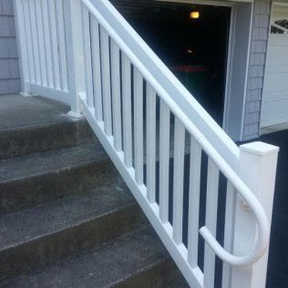 White handrail along outdoor concrete steps. Garage door open in background.