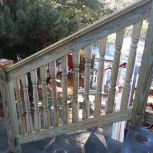 Wooden outdoor staircase with balusters, handrail, and stone steps.