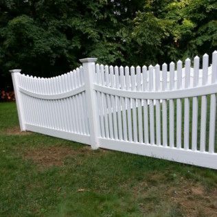 White picket fence with a curved top in a grassy yard.