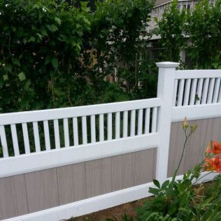 White and brown vinyl fence with diagonal slats, in front of green foliage and flowers.