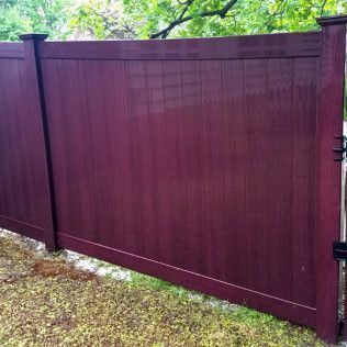Burgundy vinyl fence with a matching gate in a yard.