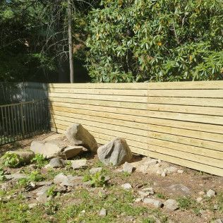 Wooden fence with rocks and greenery.