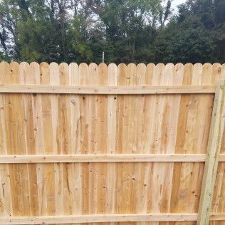 Wooden fence with scalloped top and natural wood color.