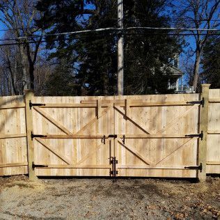 Wooden double gate with black hardware on a wooden fence.