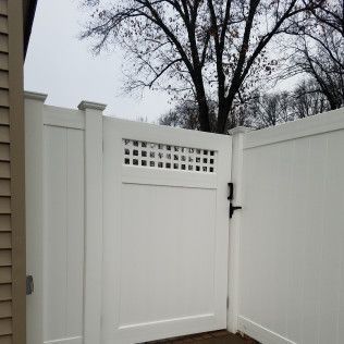 White vinyl fence with a matching gate and a decorative square lattice top section.