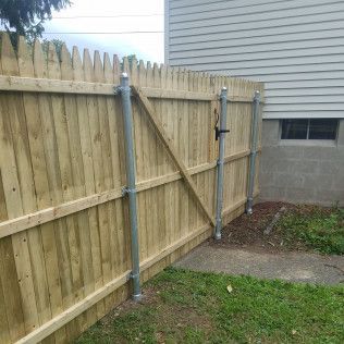 Wooden fence with a gate and metal posts, next to a house.
