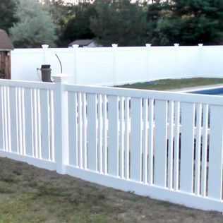 White picket fence in front of a white privacy fence surrounding a pool.