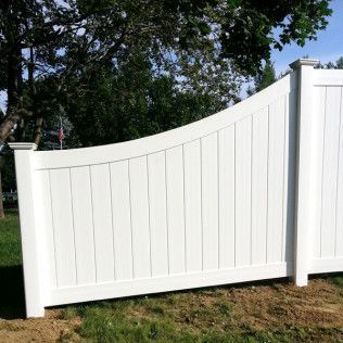 White wooden fence with arched top, outdoors in front of a tree.