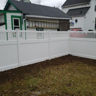 White vinyl fence in a yard, separating the property; houses in background.