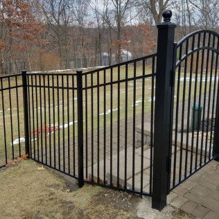 Black metal fence with gate in a yard.