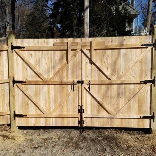 Wooden gate with black hinges and latch, part of a wooden fence; exterior setting.