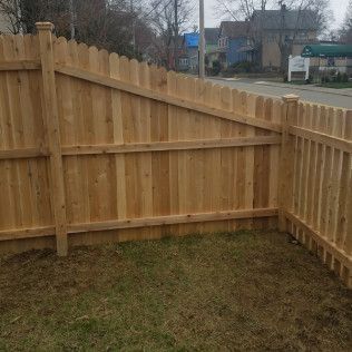 Wooden fence in yard, with picket section angled towards a street.