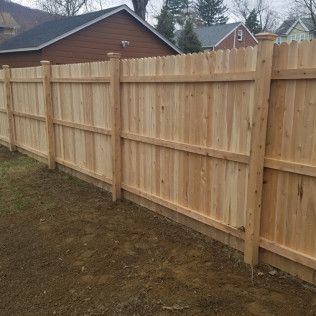 Wooden fence with pointed top in front of houses.
