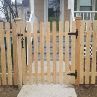 Wooden picket fence with gate in front of a house.