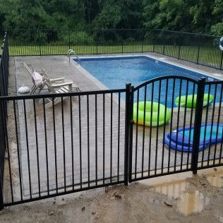 Black metal fence surrounds a backyard pool with inflatable toys.