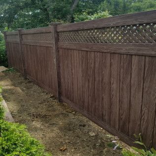 Brown wooden privacy fence with lattice detail in a yard.