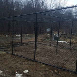 Black chain-link fence enclosure in a brown, outdoor setting.