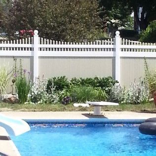Swimming pool with diving board, bordered by a white picket fence and a garden.