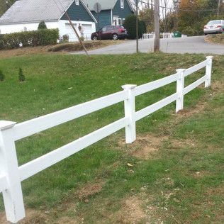 White picket fence in front yard, two-story house in the background, a car in the driveway.
