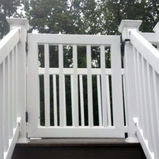 White picket gate on a deck with stairs; safety feature with vertical bars.