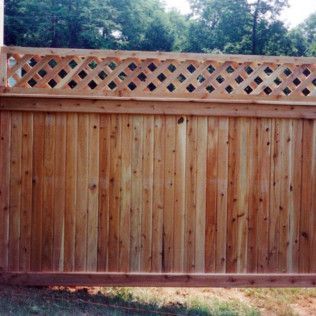 Wooden privacy fence with lattice top, natural wood color, outdoors.