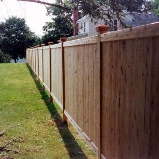 Wooden privacy fence in a grassy yard, with a house in the background.