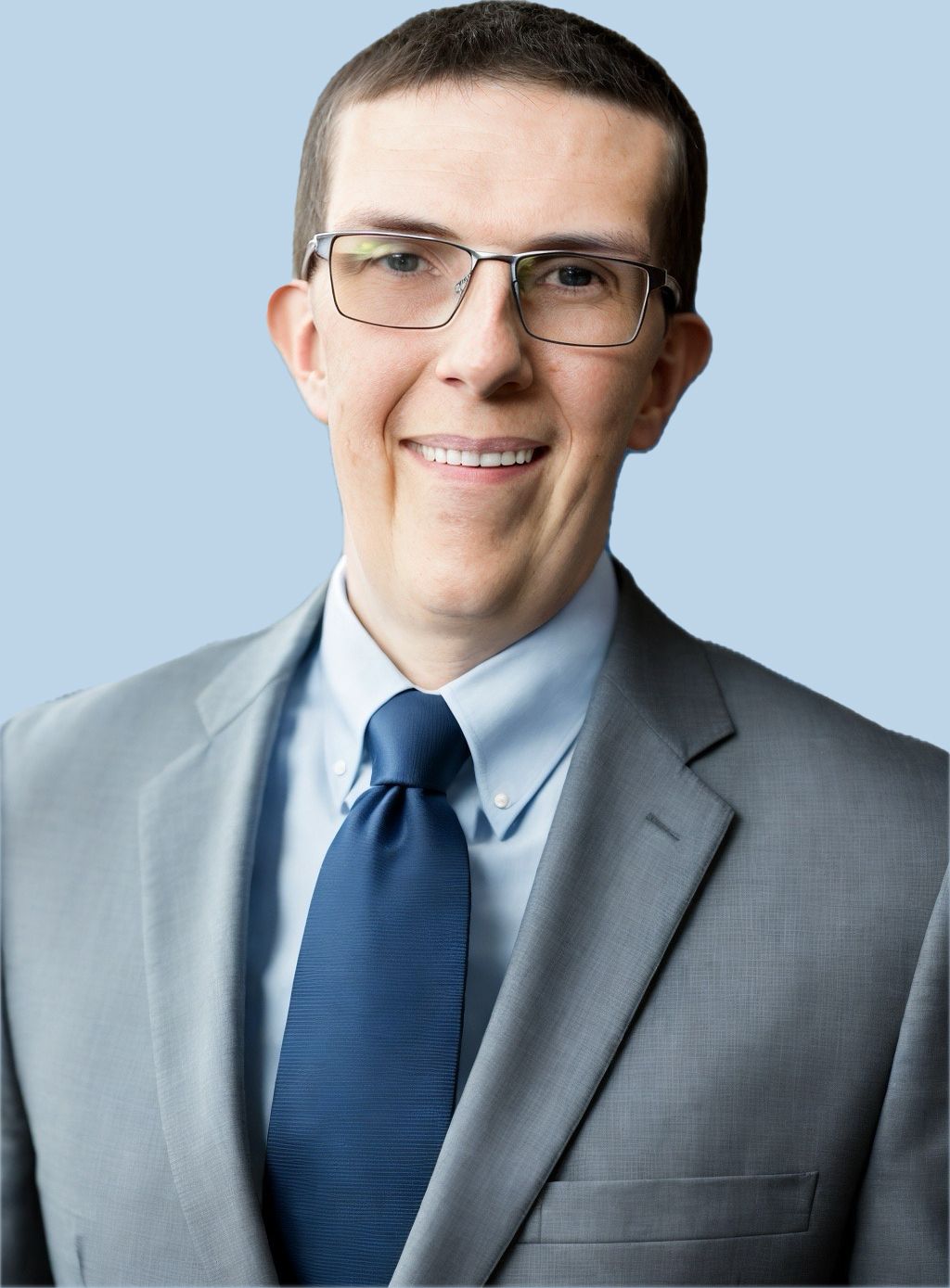 A handsome man in a suit and tie is smiling for the camera.