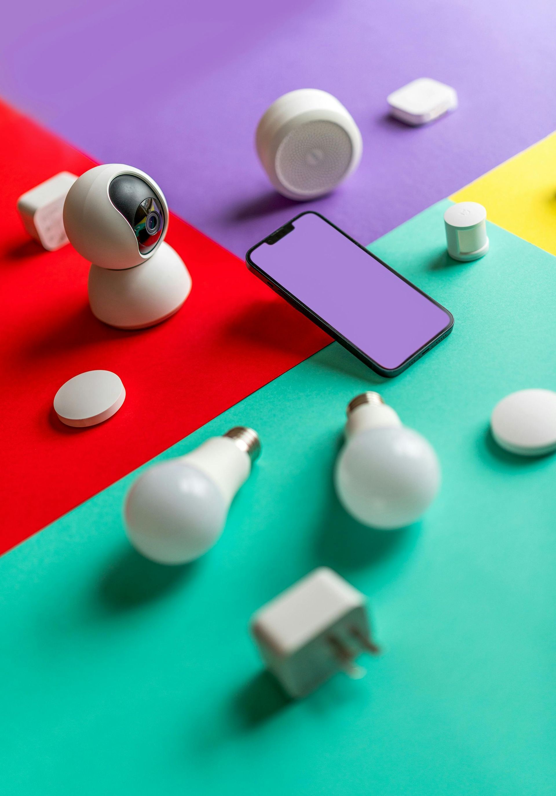 A colorful table with a cell phone , light bulbs , and a camera.