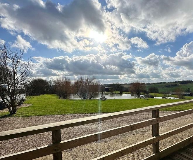A view of a field from a deck with a wooden fence.