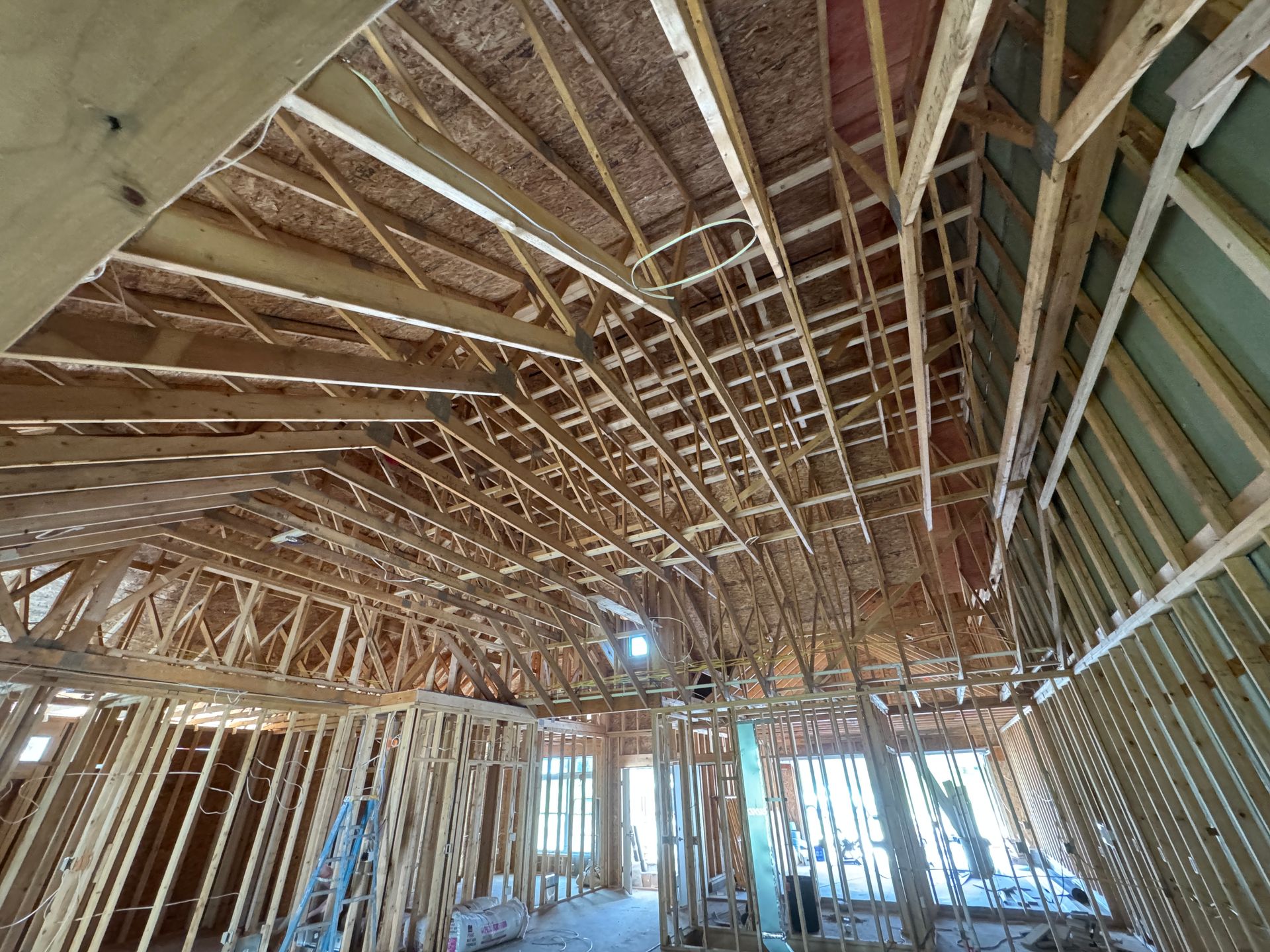 Wooden framework of a building's interior, showing walls, ceiling, and rafters under construction.